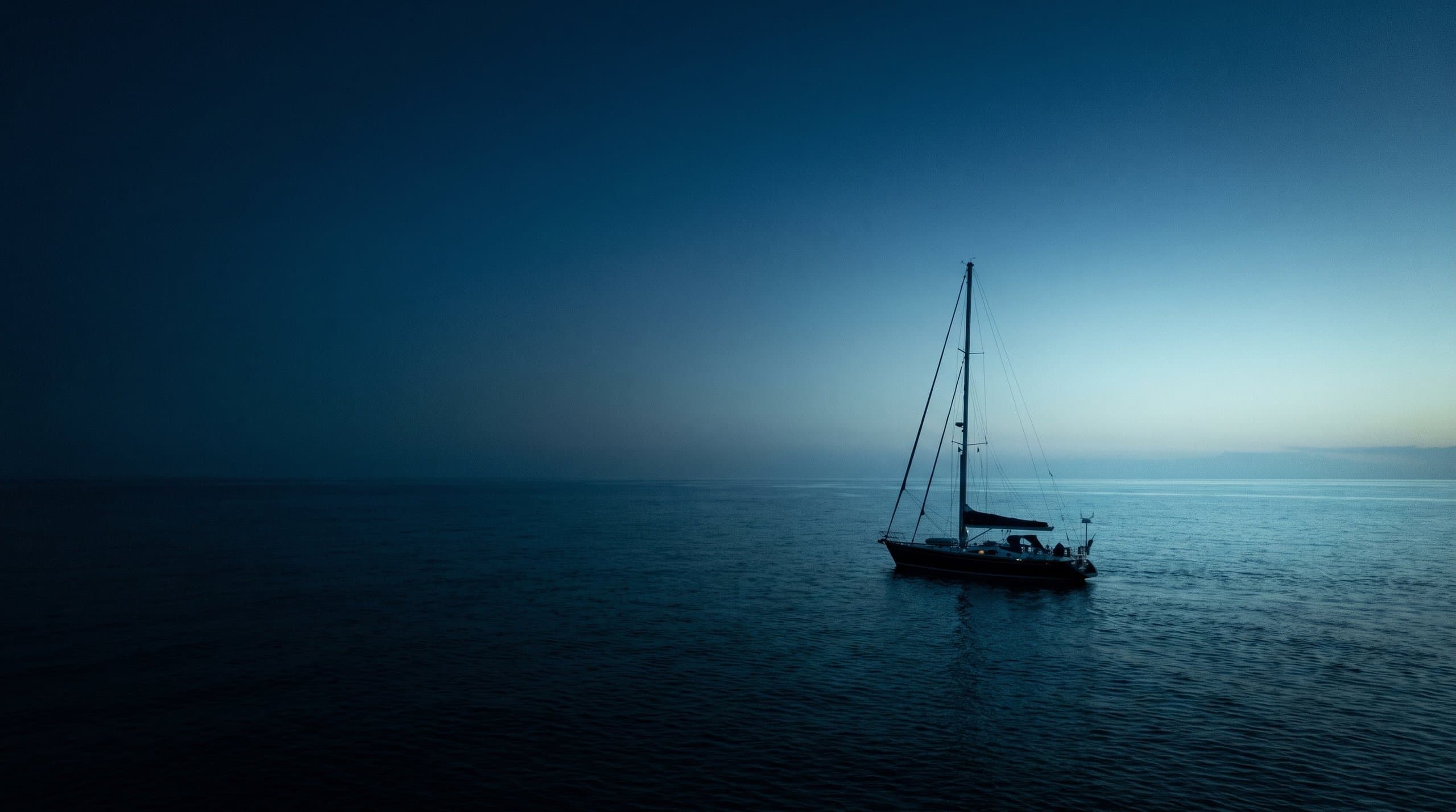 Barca a vela sbandata a vele spiegate in mare aperto durante una traversata d'altura, senza terra in vista