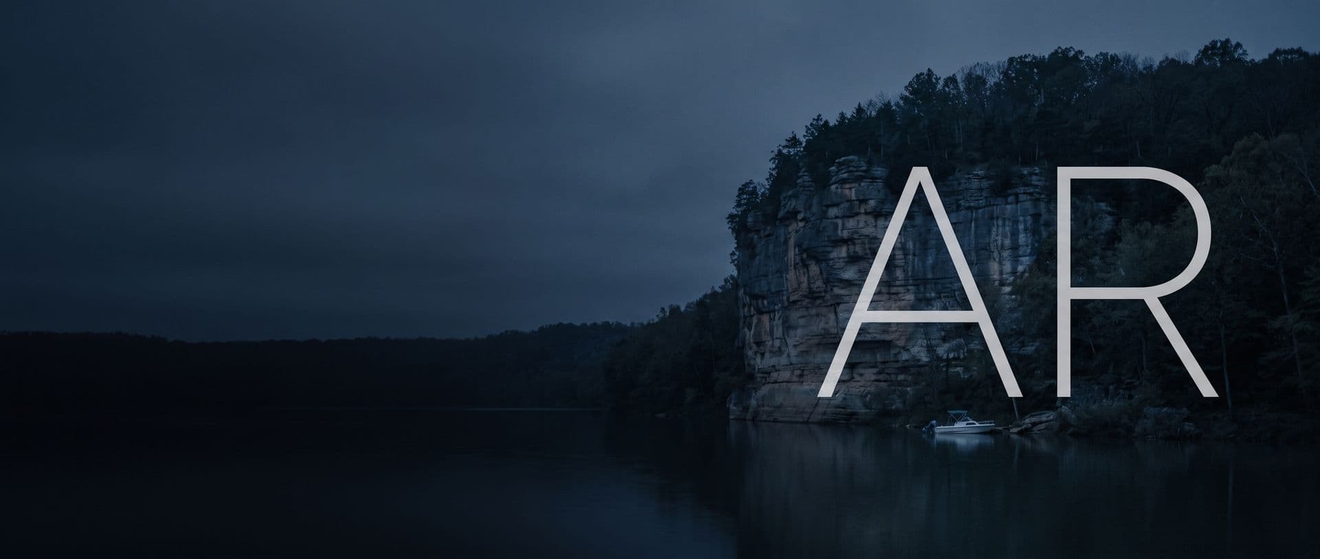 An Ozark limestone bluff on the Buffalo National River at dusk, a small boat moored below it, with the letters AR in the sky