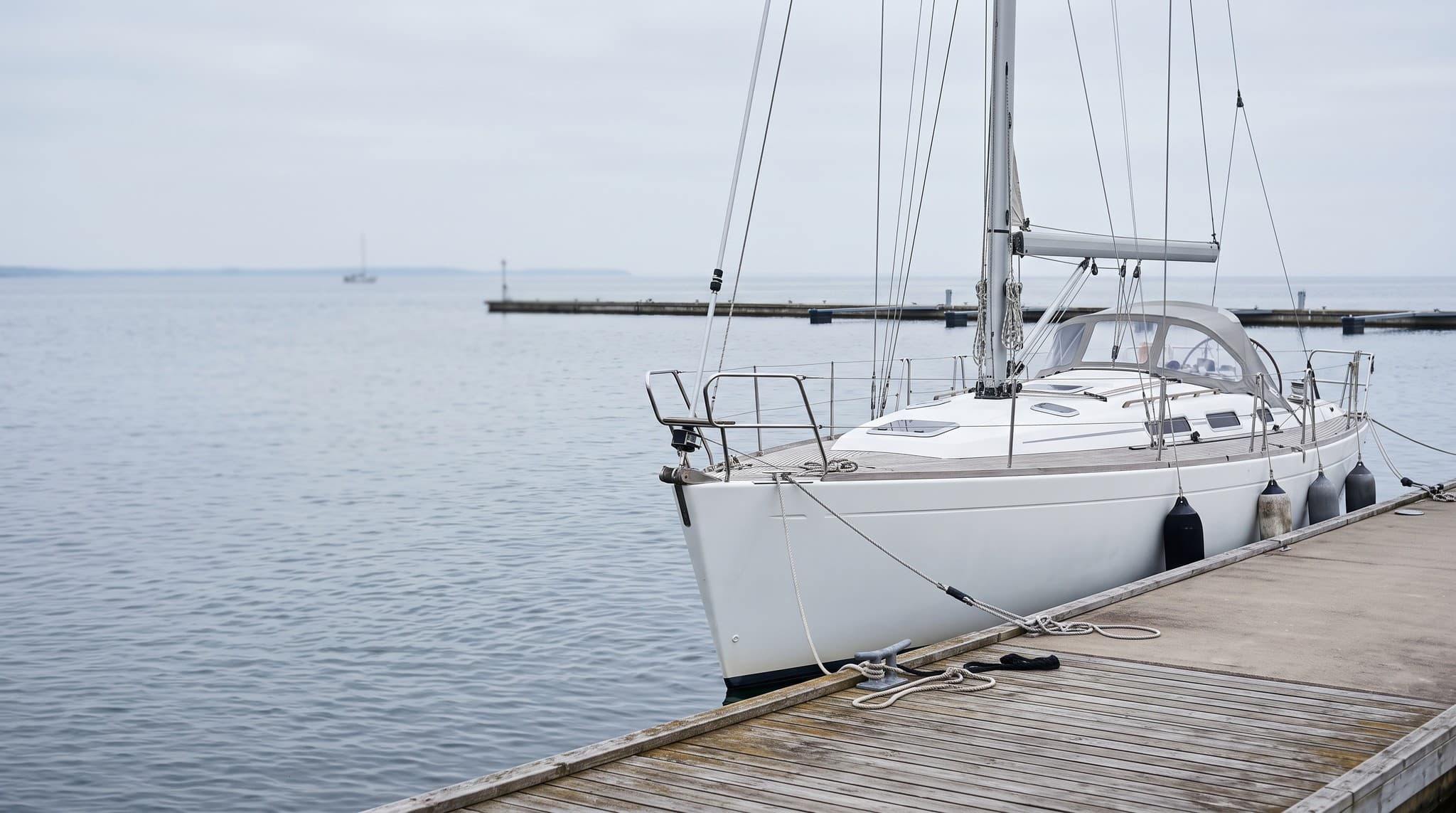 Zwölf Meter lange Fahrtensegelyacht längsseits an einem ruhigen Ostsee-Steg im weichen Morgenlicht