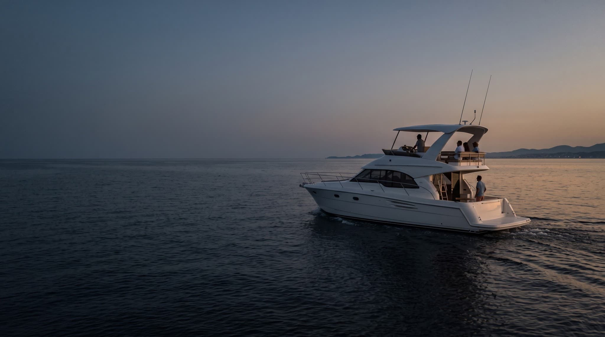 Weiße Flybridge-Motoryacht von etwa fünfzehn Metern in der Abenddämmerung auf ruhiger See, Crew an der Flybridge und im Cockpit.