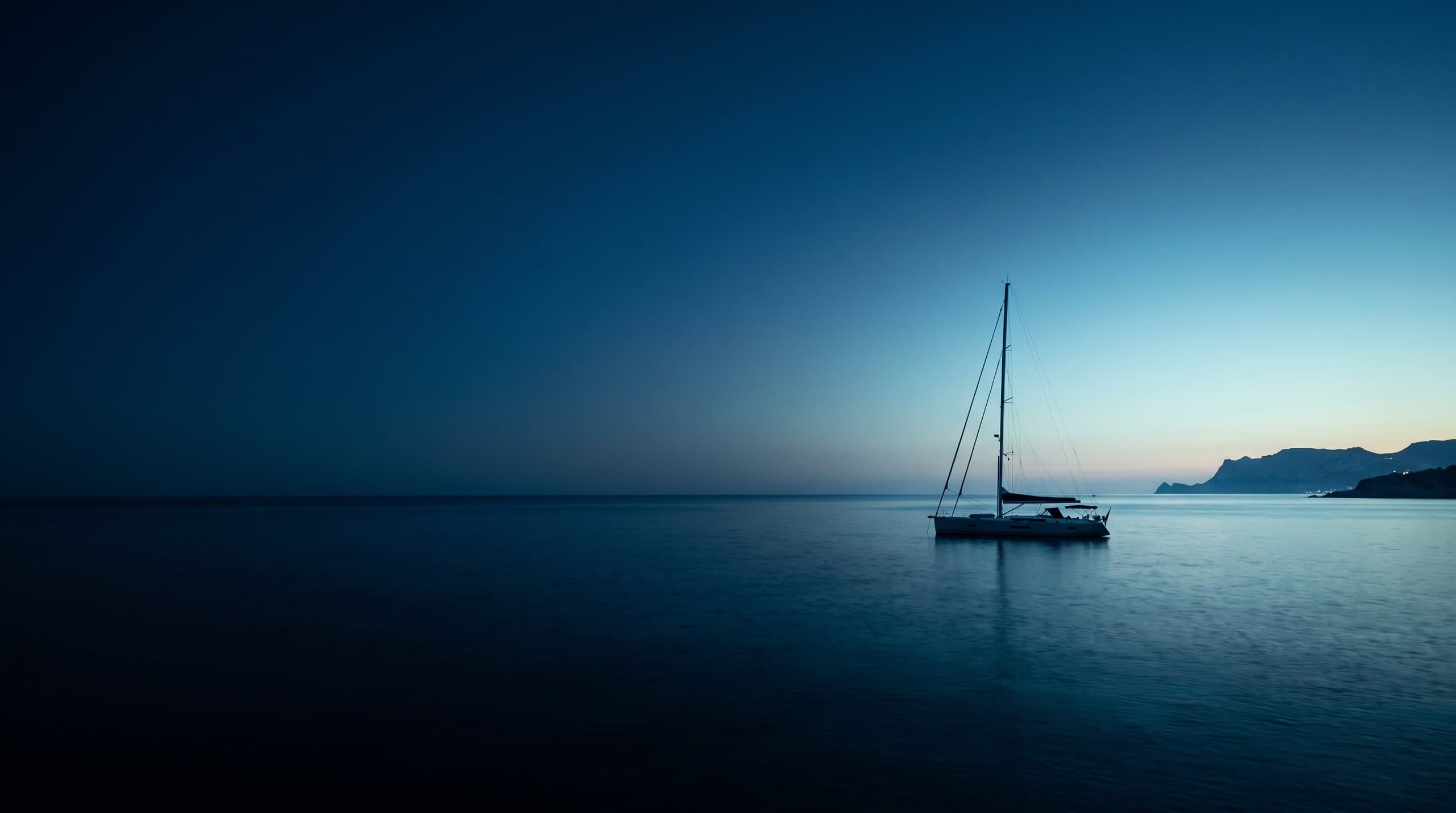 Sailing yacht at anchor in a turquoise Balearic cove in warm afternoon light
