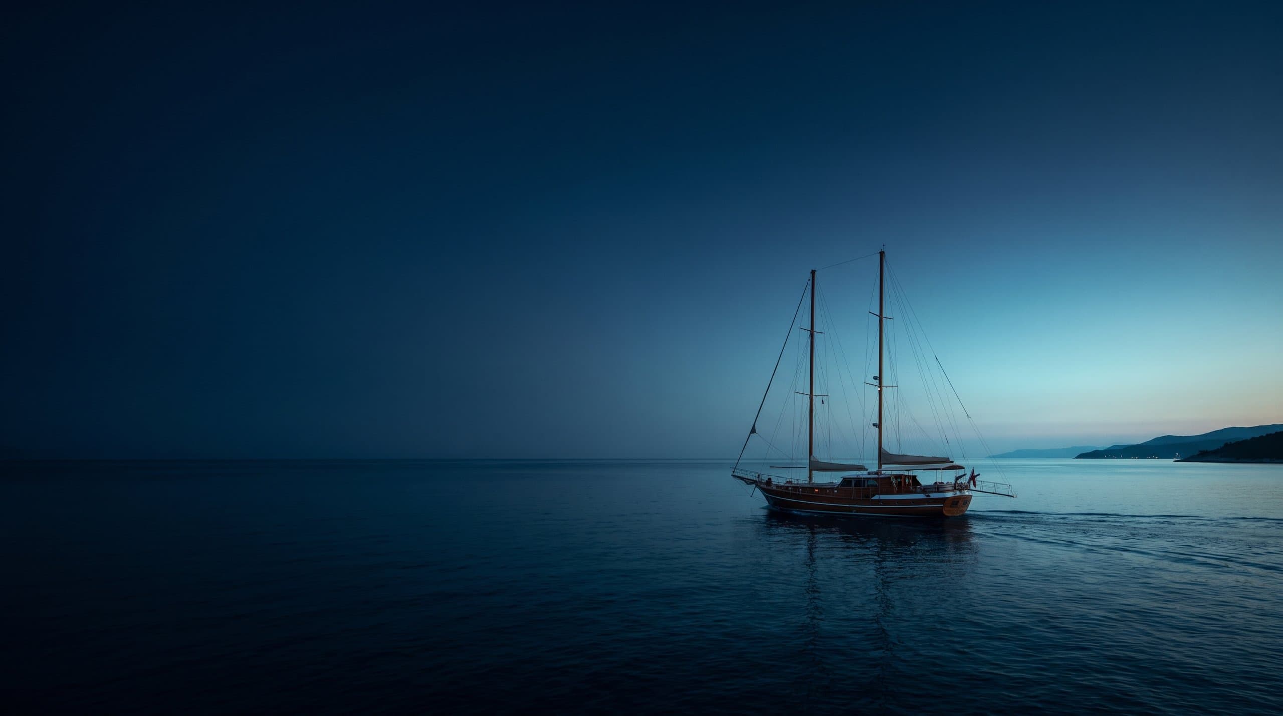 Voilier au mouillage dans une baie turque turquoise bordée de pins sous une lumière chaude de fin d'après-midi